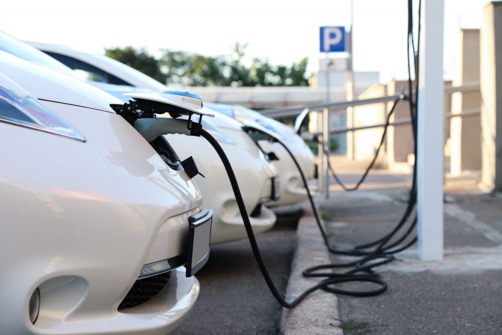 Tre hvite Nissan Leaf lader på enkel ladestasjon. Når man har kjøpt elbil kan det være smart å ha elbillader hjemme.